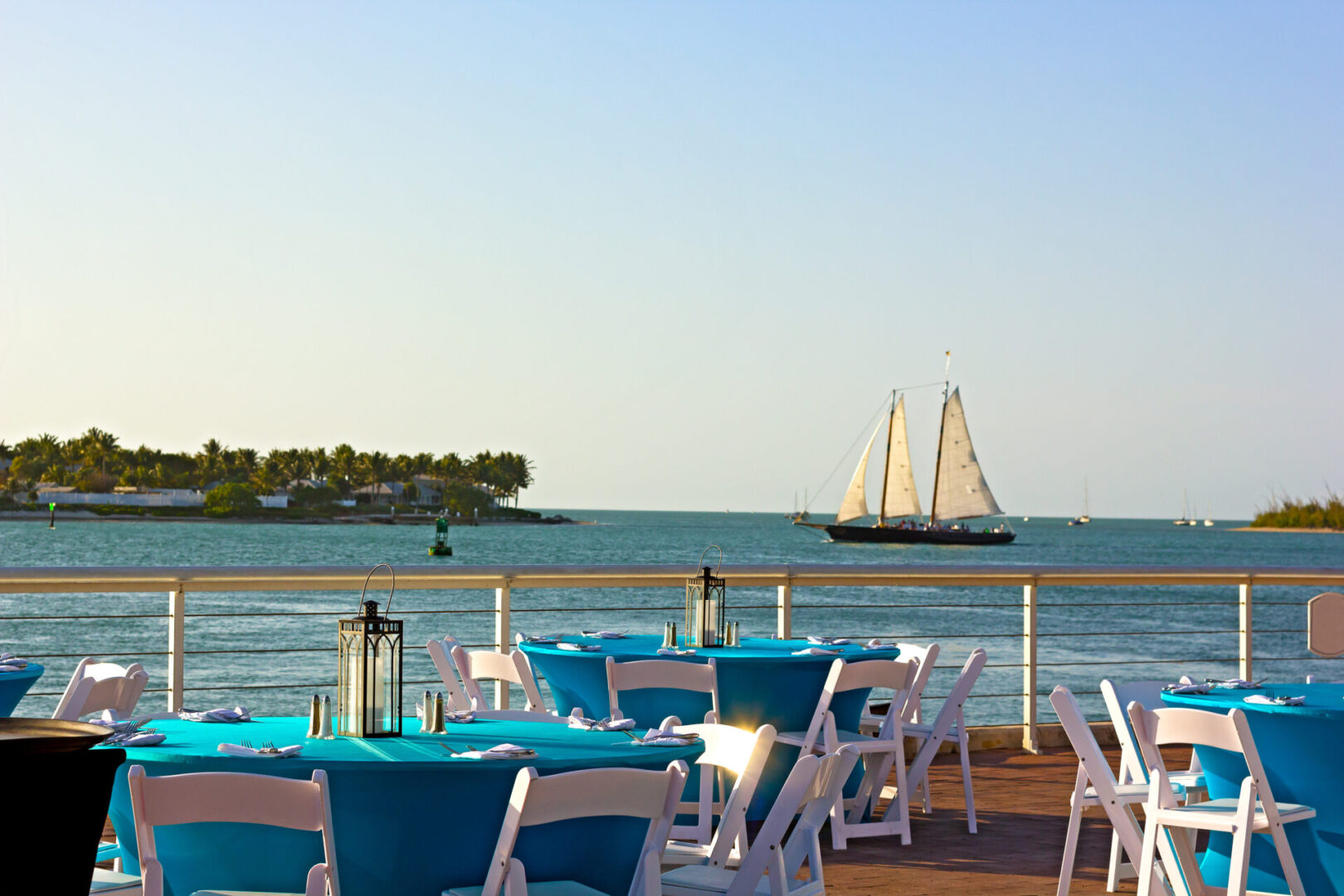 Sunset at Key West waterfront. A sea view of dining area with sailboat passing by.